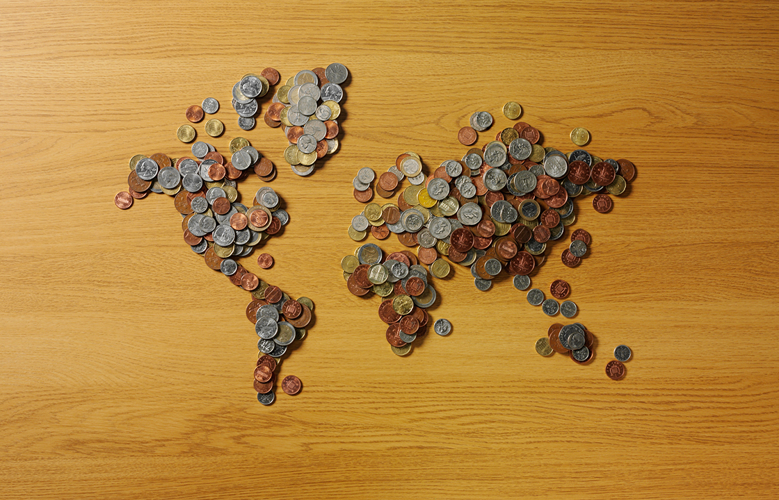 pièces de monnaie de différent pays, éparpillées sur une surface en bois.